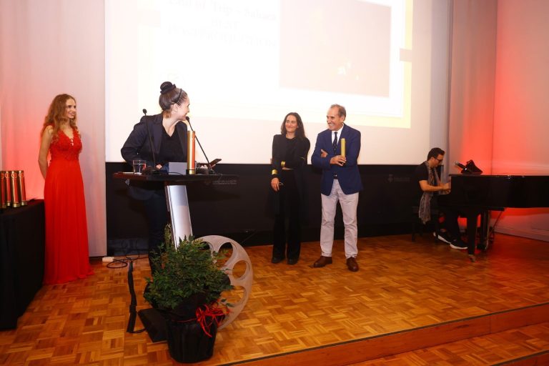 Lliurament de premis a l’escenari: dues persones amb el trofeu del festival, la presentadora i un pianista