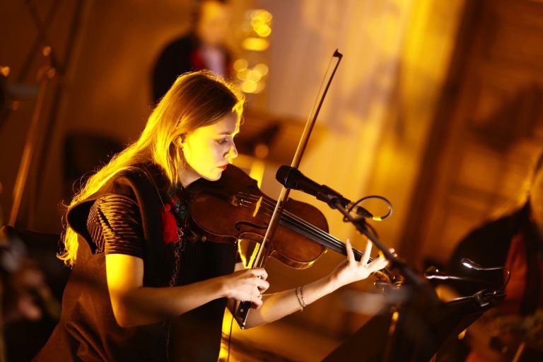 Violinista tocant sota una llum càlida durant un concert del festival